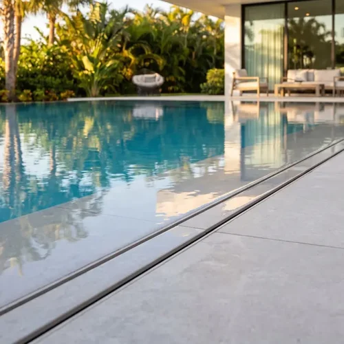 Grelha linear para áreas externas invisível em alumínio instalada no piso de porcelanato junto à borda de piscina.